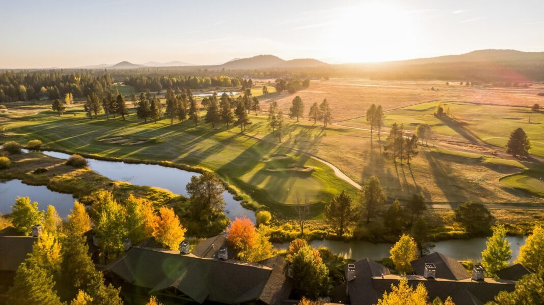 Aerial view of Sunriver Resort at golden hour — lodges, golf course, and mountains
