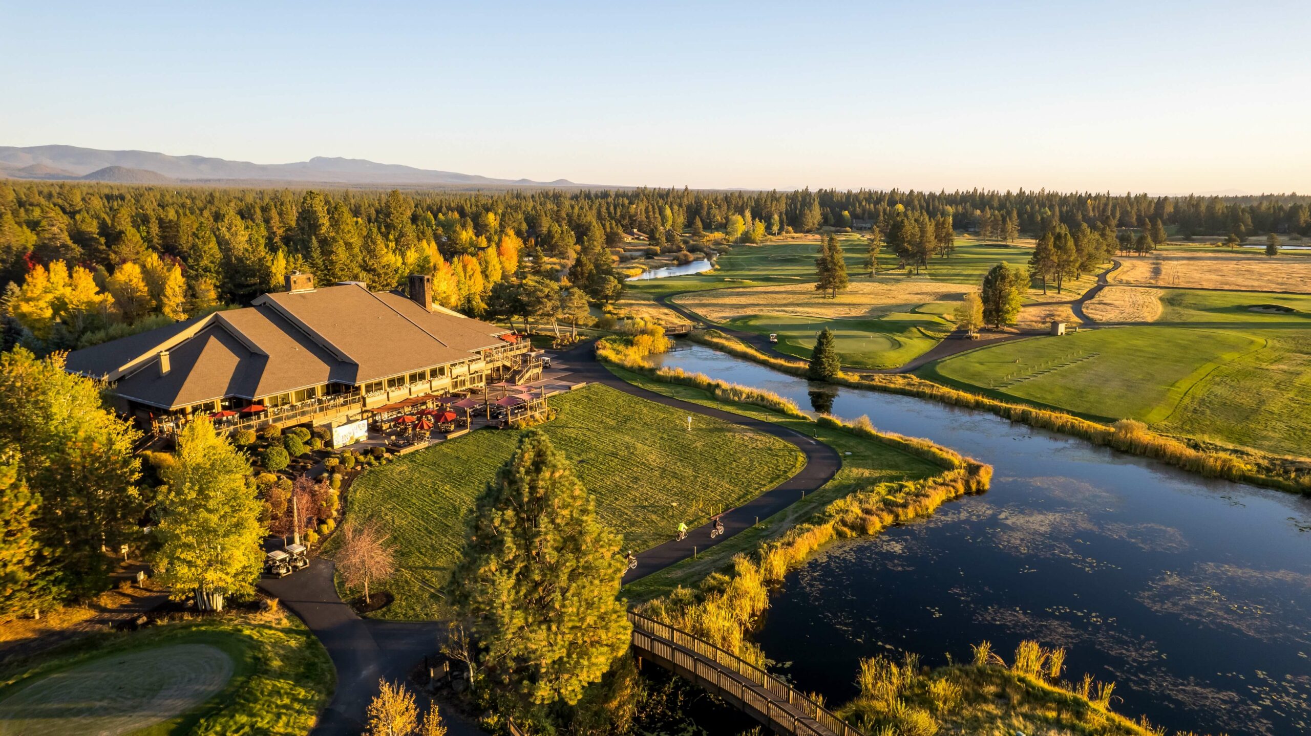 Aerial view of the lodge, river, and bridge at golden hour
